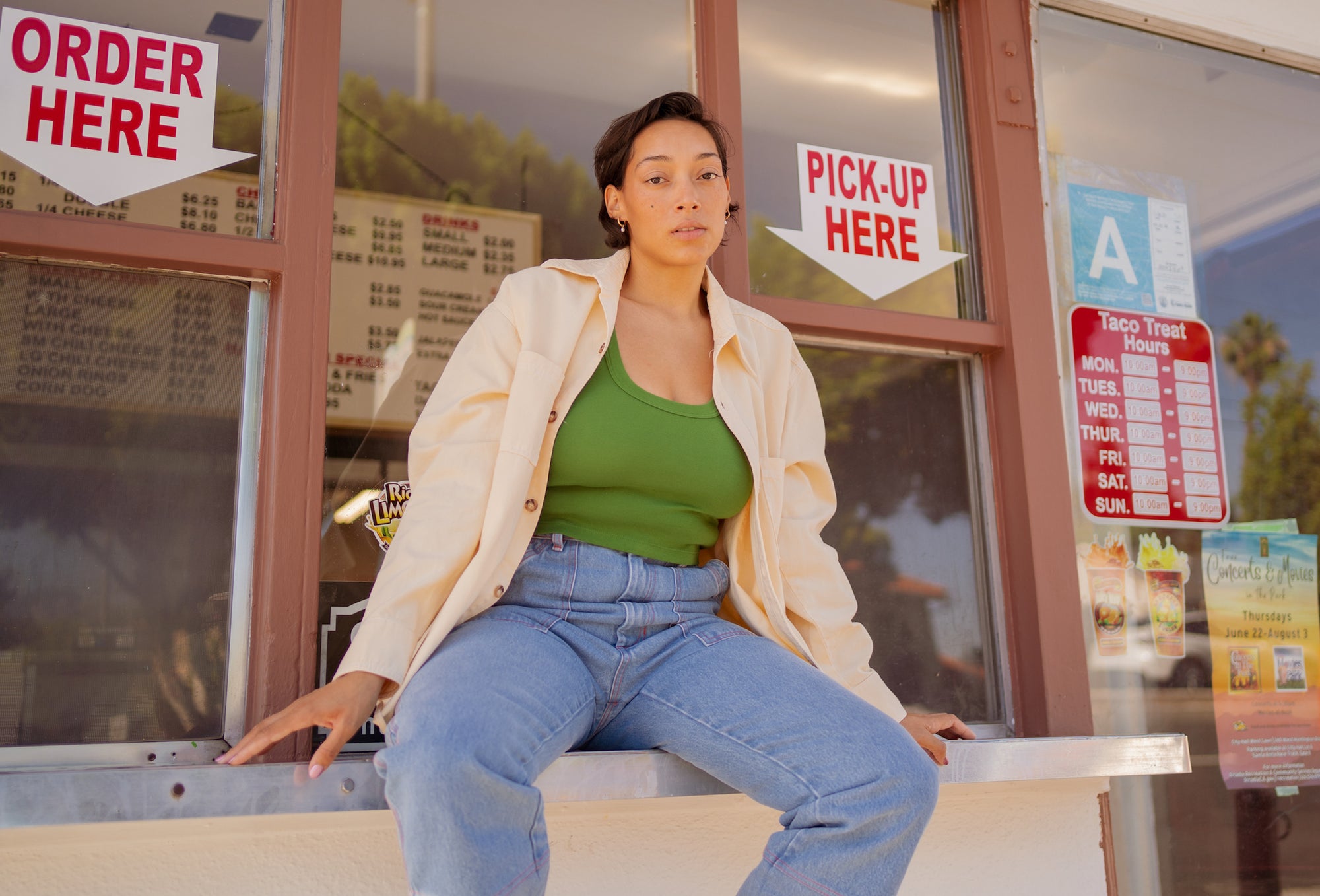 Tiara is wearing Oversize Overshirt in Vintage Off-White, Cropped Tank Top in Lawn Green, and Carpenter Jeans in Light Wash