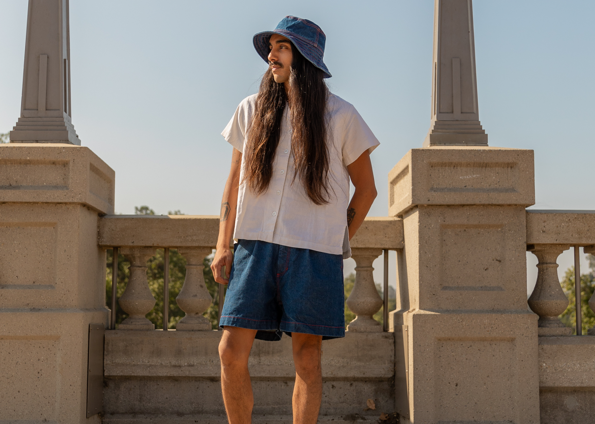Anthony is wearing Denim Bucket Hat in Dark Wash, Denim Trouser Shorts in Dark Wash and Pantry Button-Up in Vintage Tee Off-Whit