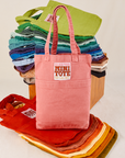 Raspberry Mini Tote Bag with a stack of bags behind