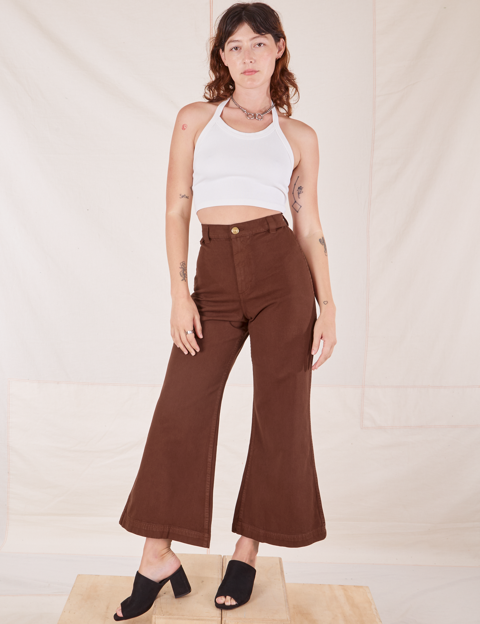 Alex is 5'8" and wearing XXS Bell Bottoms in Fudgesicle Brown paired with a Halter Top in vintage tee off-white