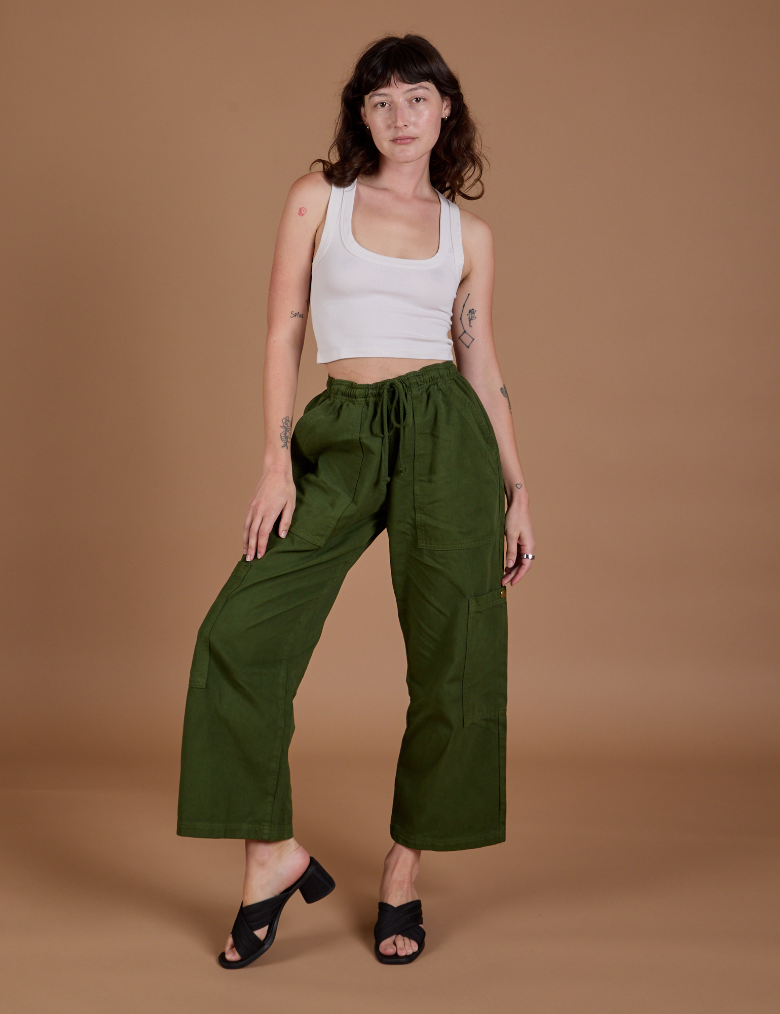 Alex is 5’8” and wearing XXS Drop Pocket Cargo Pants in Evergreen paired with a Cropped Tank in vintage tee white