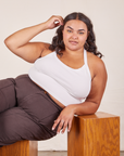 Alicia is 5'9" and wearing XL Halter Top in Vintage Off-White paired with espresso brown Western Pants. She is sitting sideways on a wooden box and her right elbow is leaning on another wooden box.