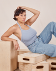 Tiara is 5'4" and wearing XS Halter Top in Periwinkle paired with light wash Sailor Jeans. She is sitting on a stack of wooden crates.