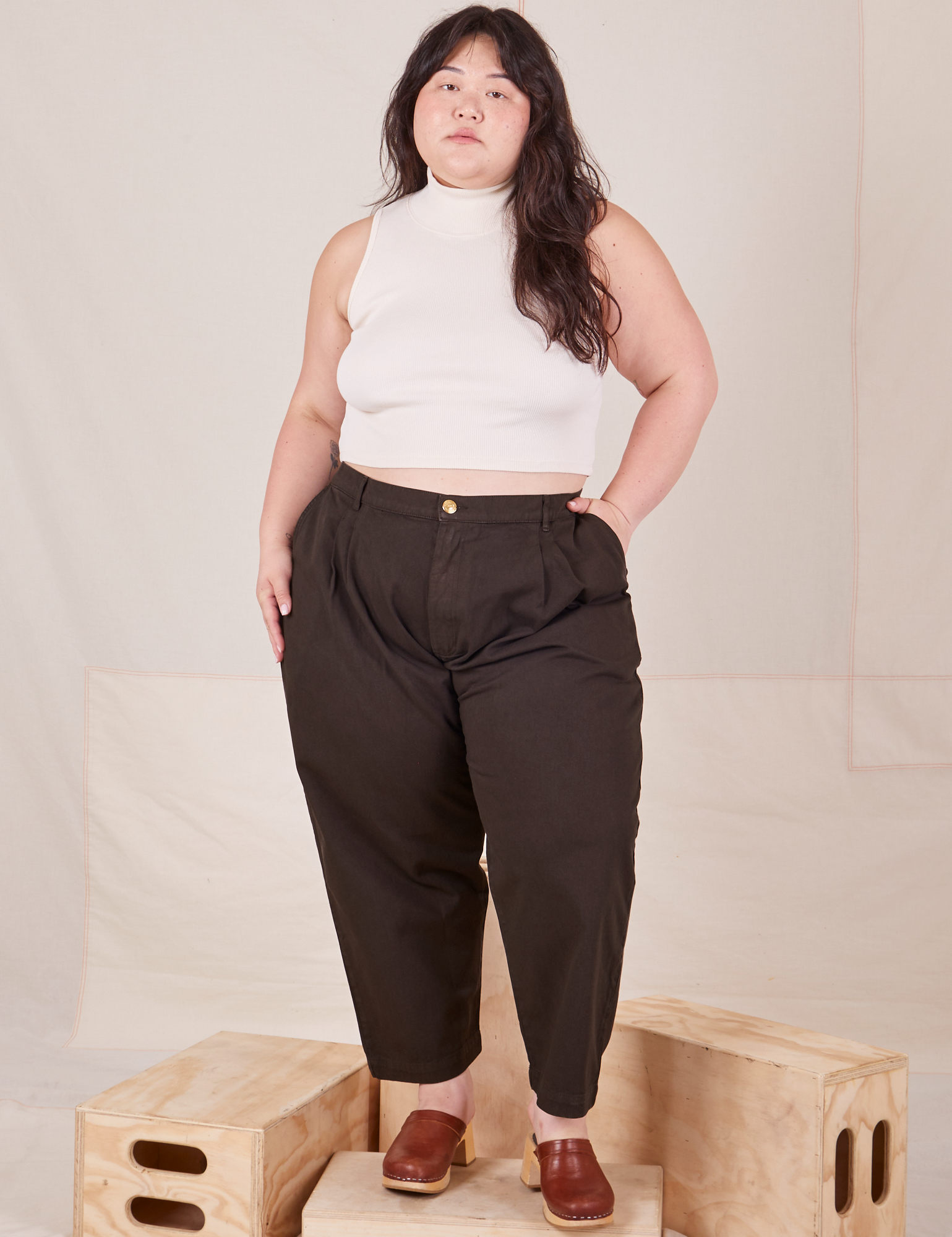 Ashley is 5'7" and wearing 1XL Petite Heavyweight Trousers in Espresso Brown paired with Sleeveless Turtleneck in vintage tee off-white