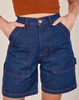 Carpenter Shorts in Dark Wash close up on Alex. She has both hands in the front pockets.