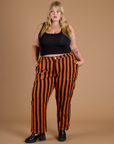 Juliet is 5’7” and wearing 2XL Black Stripe Work Pants in Construction Orange paired with black cropped tank