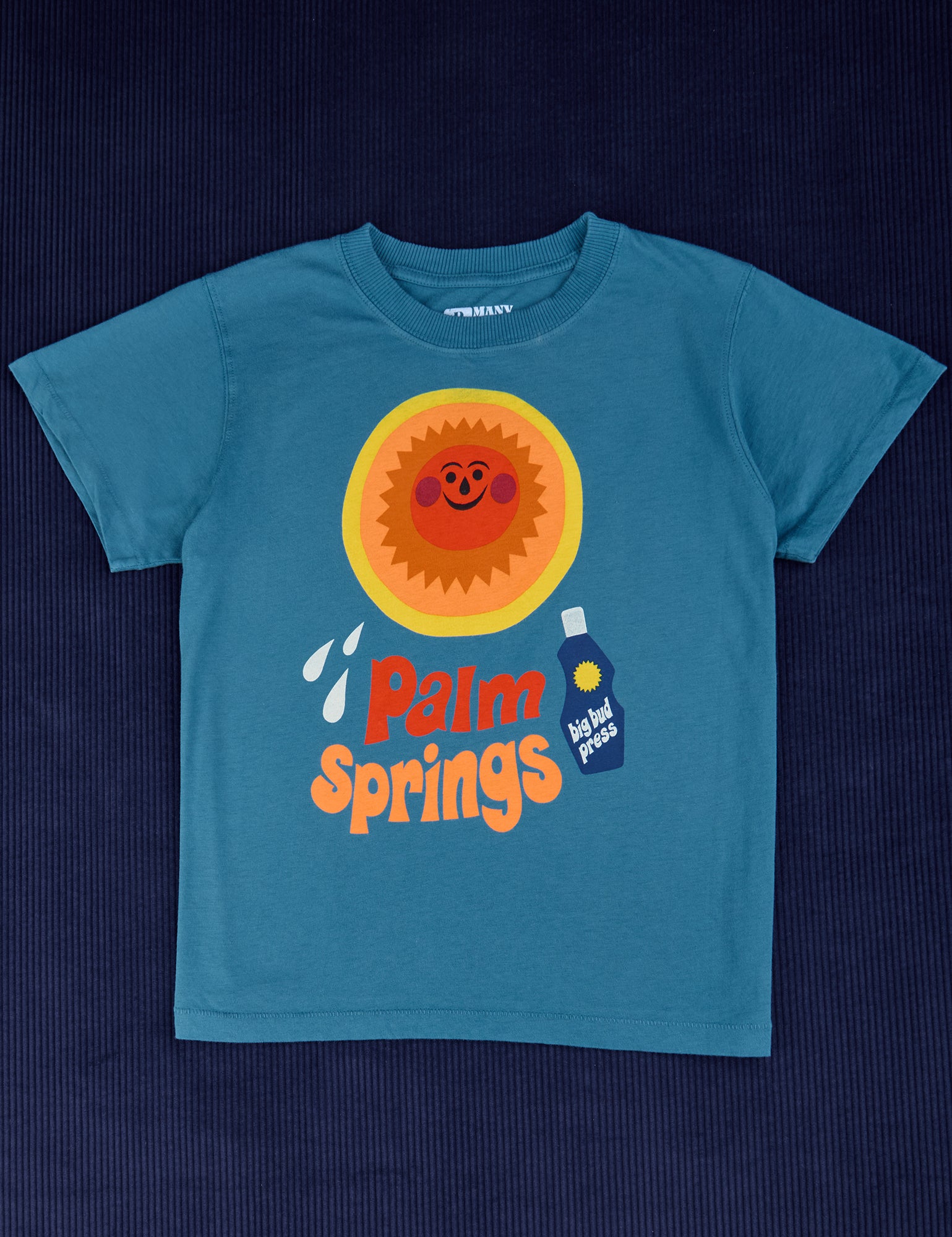 Palm Springs Tourist Tee with sun block lotion and illustrated smiling sun. Printed on a marine blue tee.