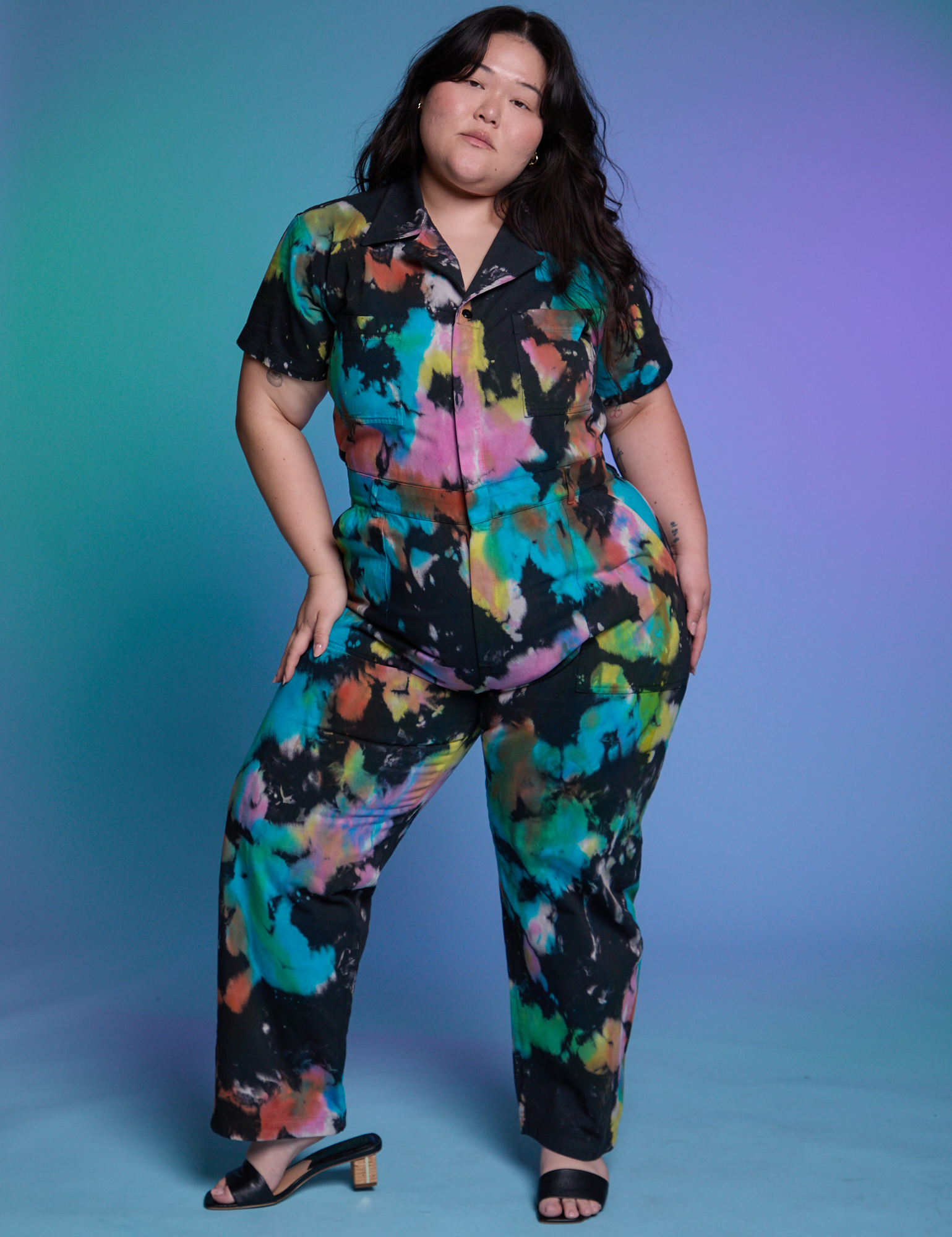 Ashley is 5'7" and wearing 1XL Short Sleeve Jumpsuit in Rainbow Magic Waters