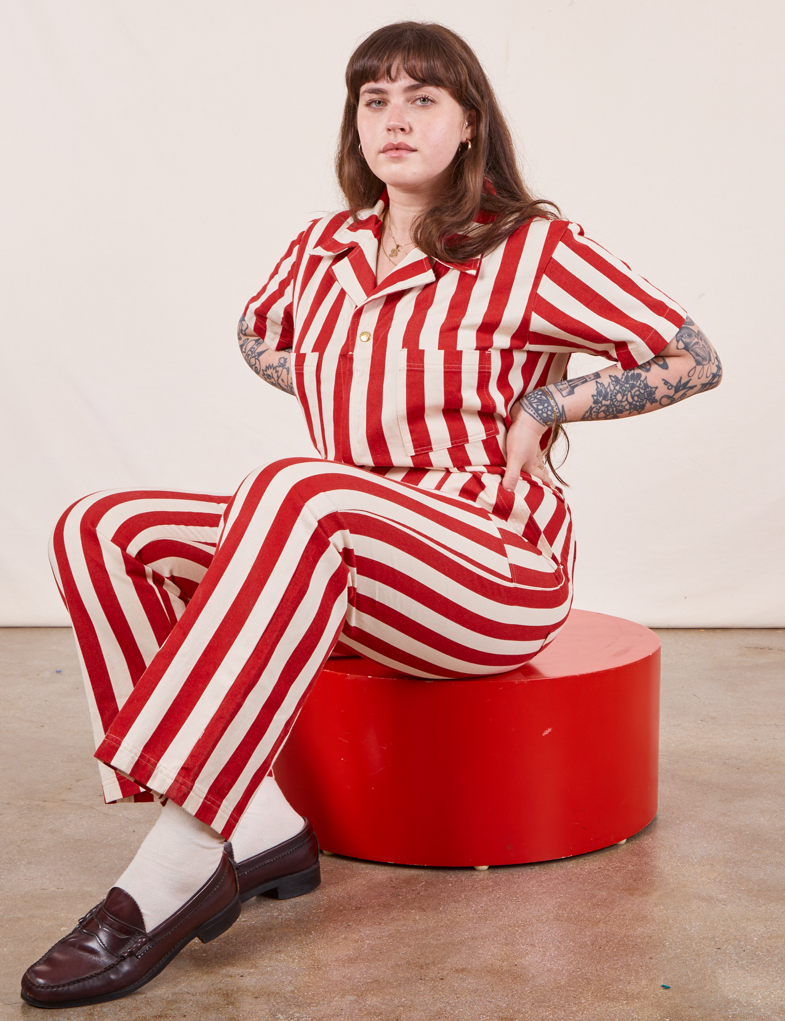 Sydney is wearing Cherry Stripe Jumpsuit sitting on a red circular platform