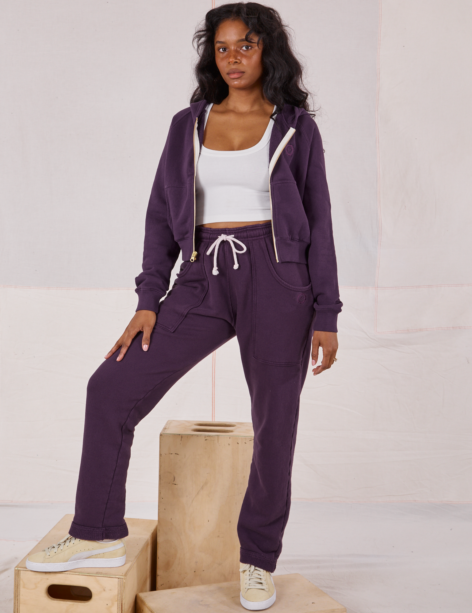 Kandia is 5'3" and wearing P Rolled Cuff Sweat Pants in Nebula Purple paired with matching Cropped Zip Hoodie and a Cropped Tank in vintage tee off-white underneath