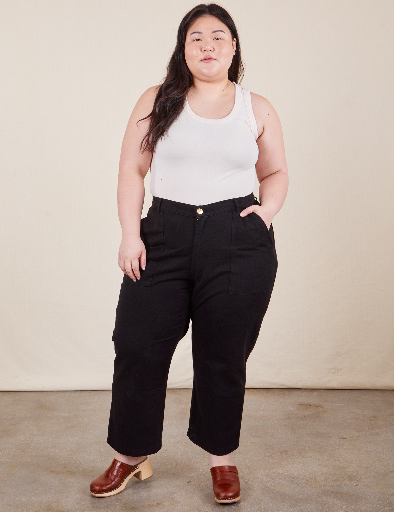 Ashley is 5&#39;7&quot; and wearing Petite 1XL Work Pants in Basic Black paired with vintage off-white tank