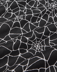 Spider Webs Pantry Button-Up detail close up. Black fabric with white spiderweb print