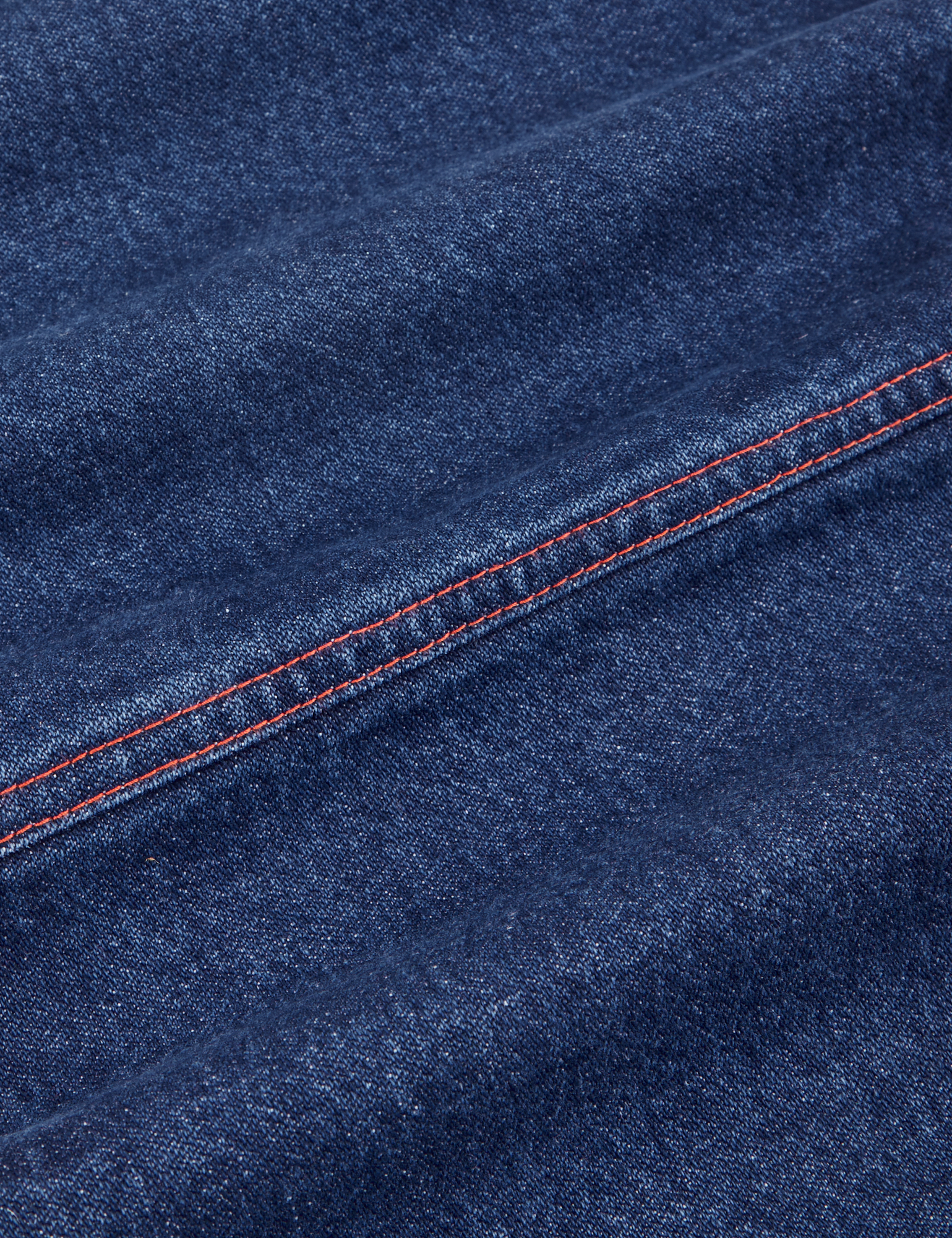 Carpenter Jeans in Dark Wash fabric detail close up with contrast red stitching.