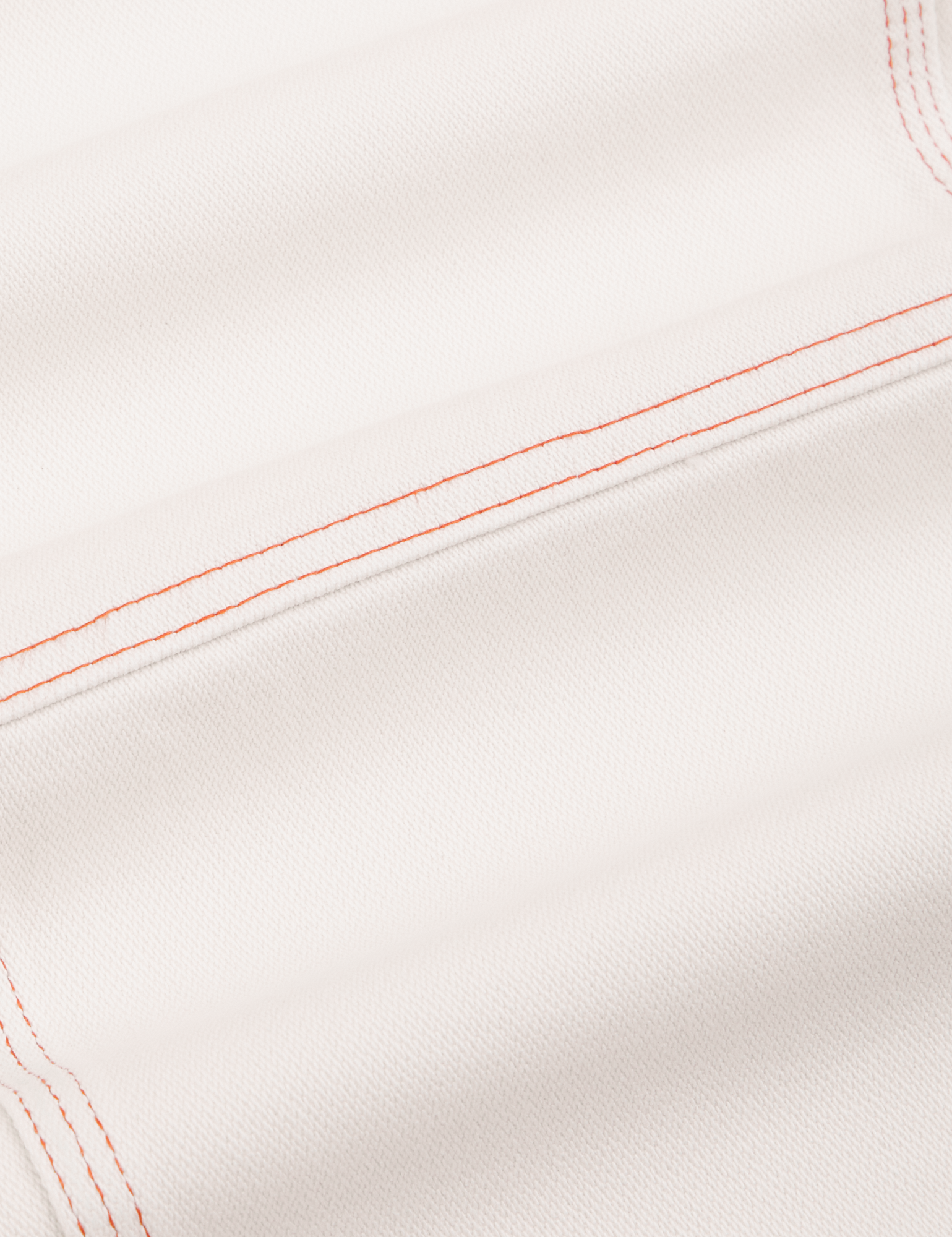 Carpenter Jeans in Vintage Tee Off-White fabric detail close up. Contrast orange stitching.