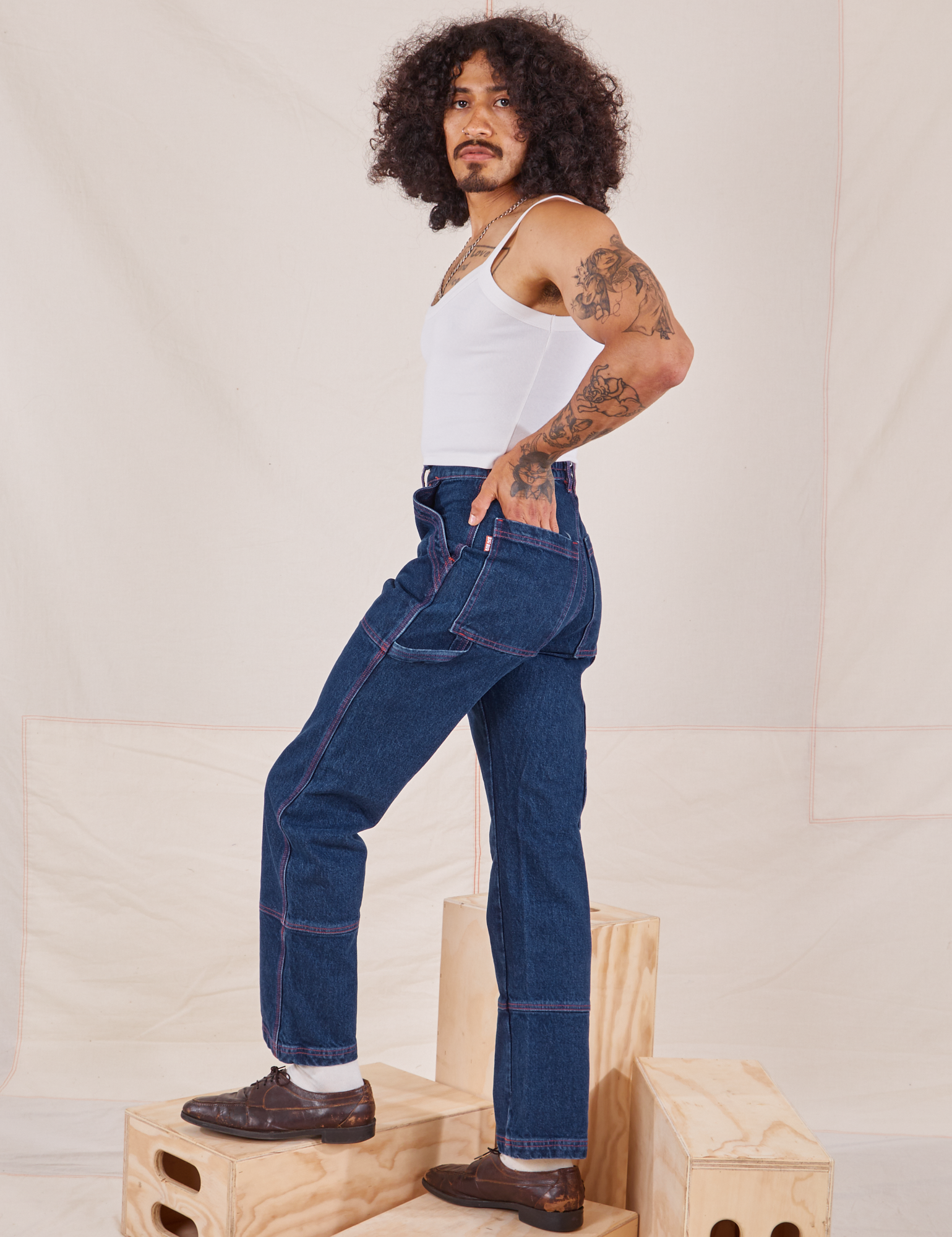 Side view of Carpenter Jeans in Dark Wash and Cropped Cami in vintage tee off-white worn by Jesse