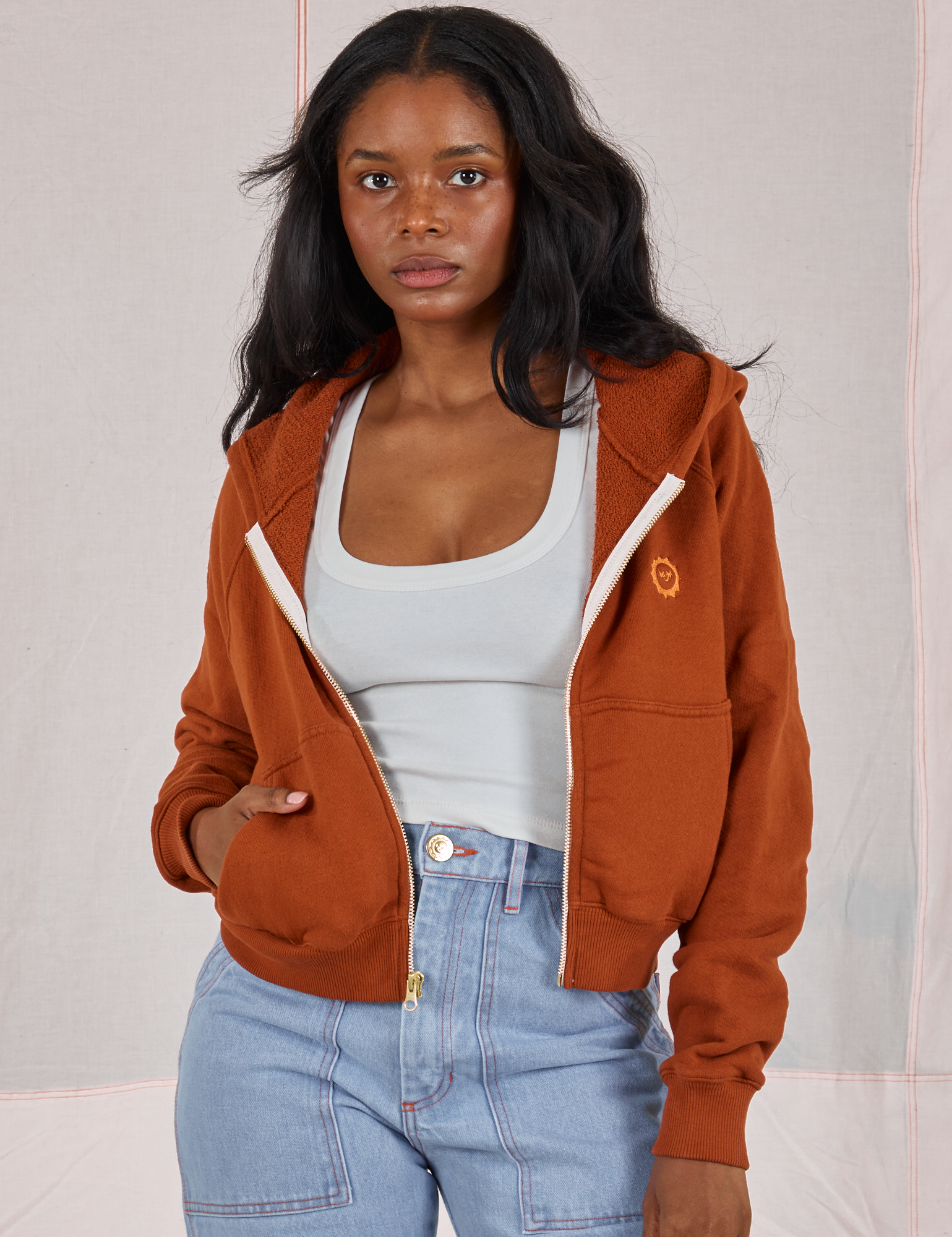 Kandia is 5&#39;3&quot; and wearing P Cropped Zip Hoodie in Burnt Terracotta paired with a vintage off-white Cropped Tank underneath