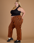 Side view of Black Stripe Work Pants in Construction Orange and black cropped tank on Juliet