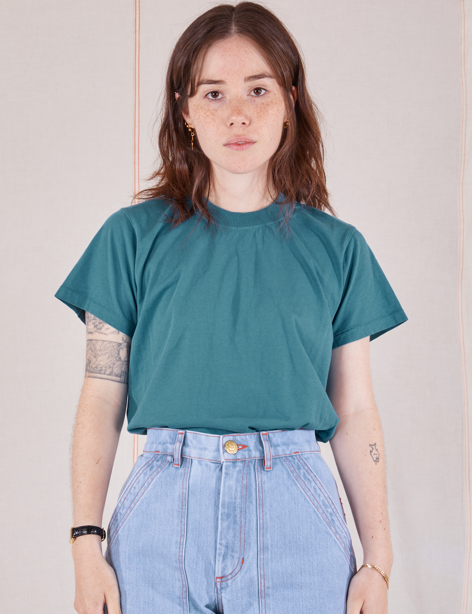 Hana is 5&#39;3&quot; and wearing P Organic Vintage Tee in Marine Blue tucked into light wash Carpenter Jeans