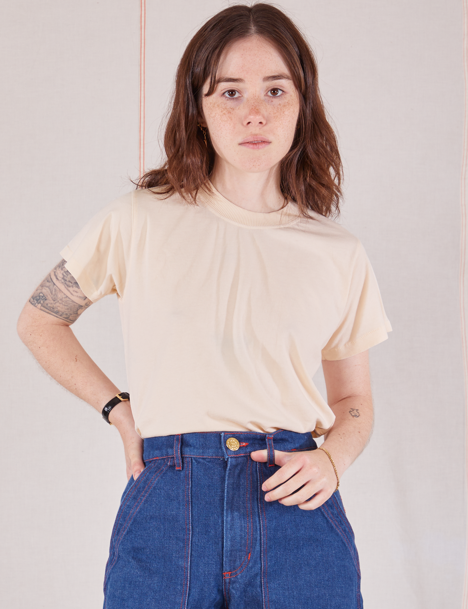 Hana is 5&#39;3&quot; and wearing P Organic Vintage Tee in Vintage Tee Off-White tucked into dark wash Carpenter Jeans