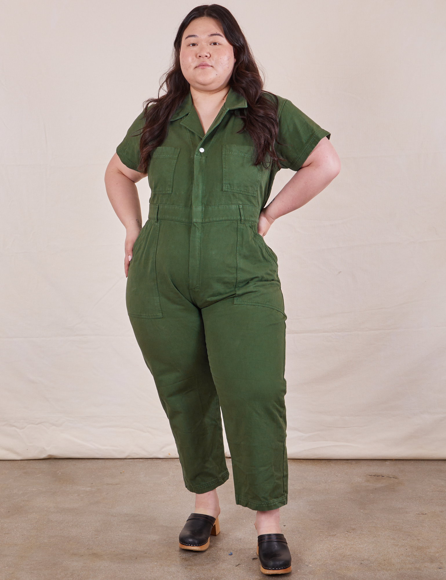 Ashley is 5’7” and wearing 1XL Petite Short Sleeve Jumpsuit in Dark Emerald Green