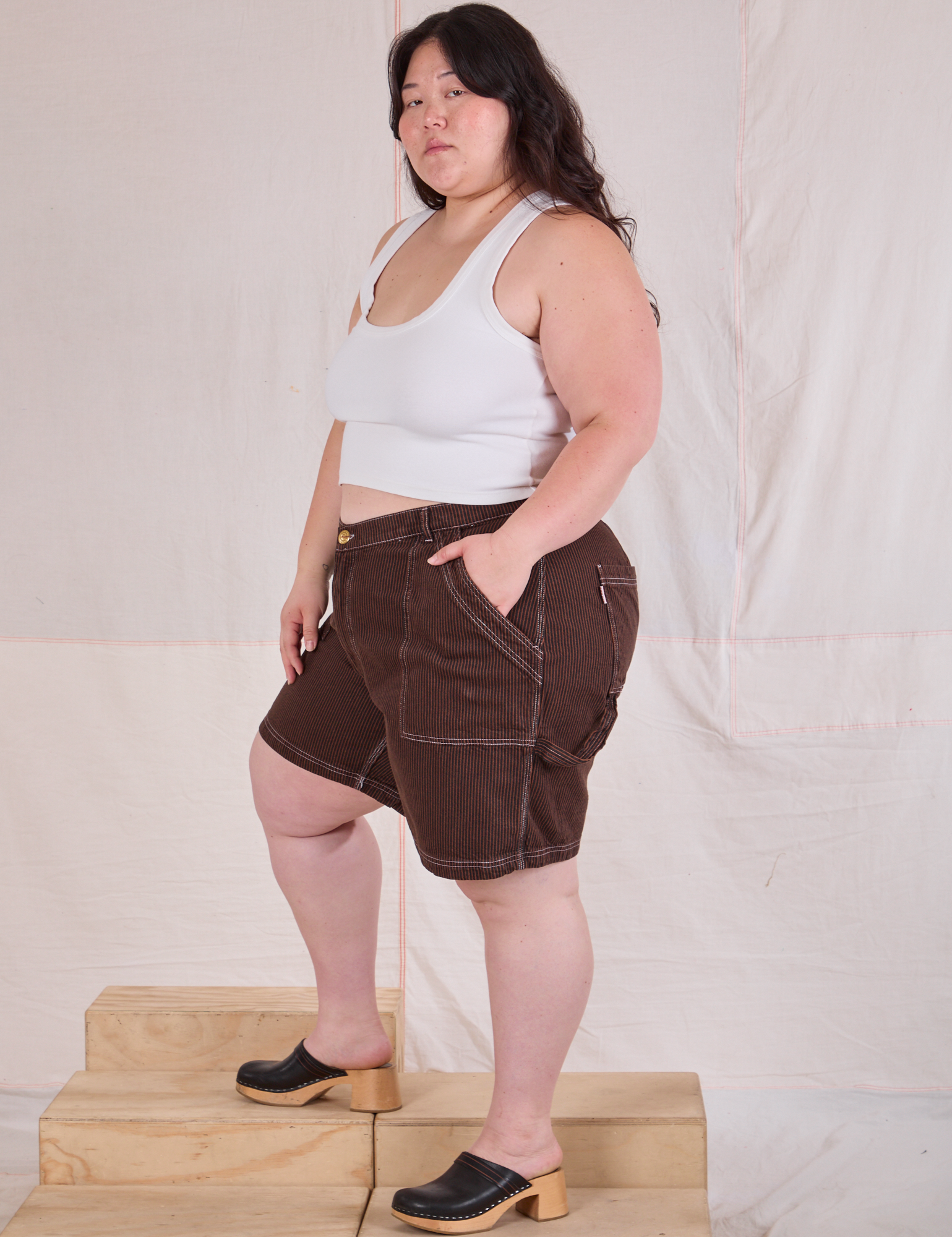 Side view of Railroad Carpenter Shorts in Fudgesicle Brown and Cropped Tank in Vintage Tee Off-White on Ashley