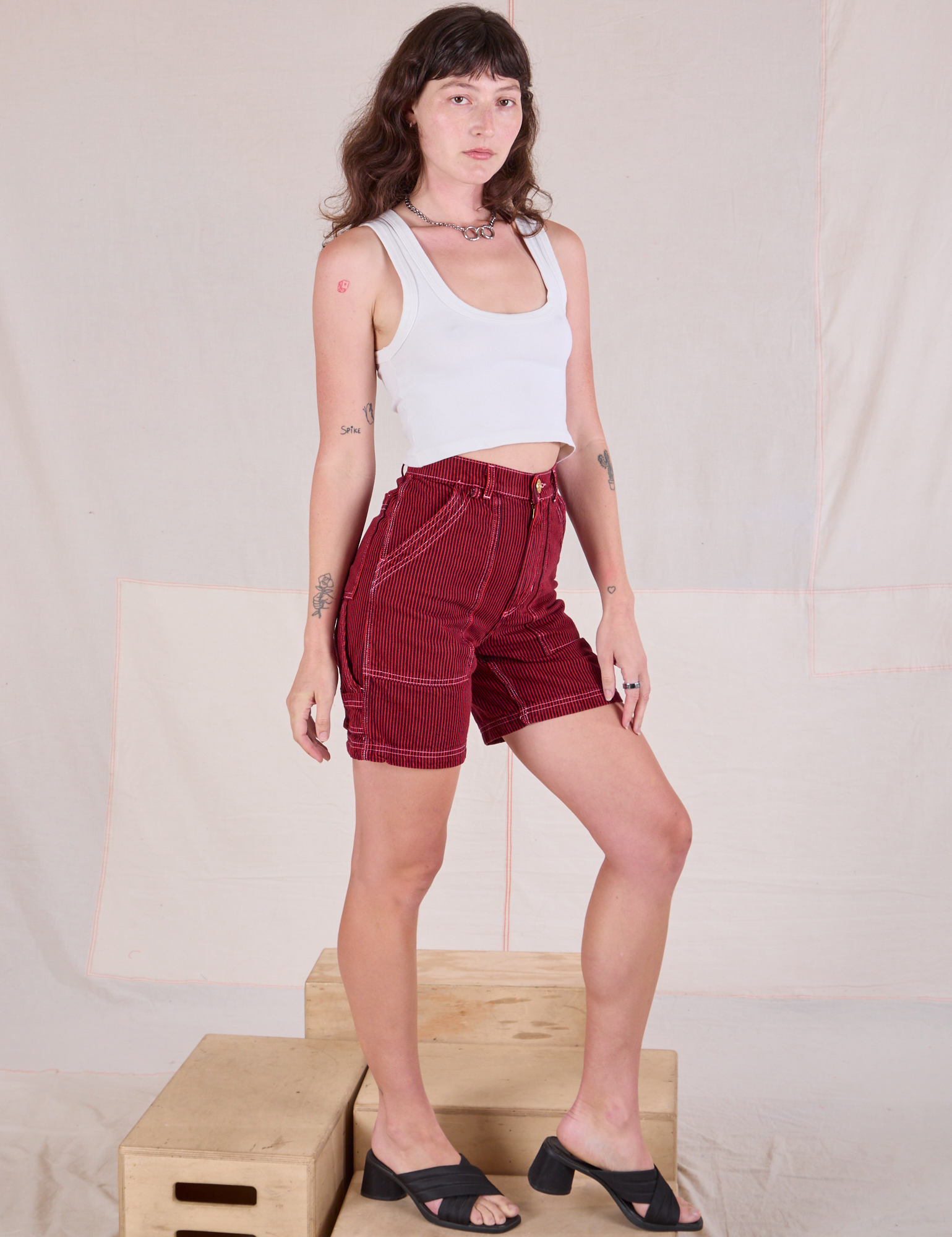 Angled front view of Railroad Carpenter Shorts in Mustang Red and Cropped Tank in Vintage Tee Off-White on Alex