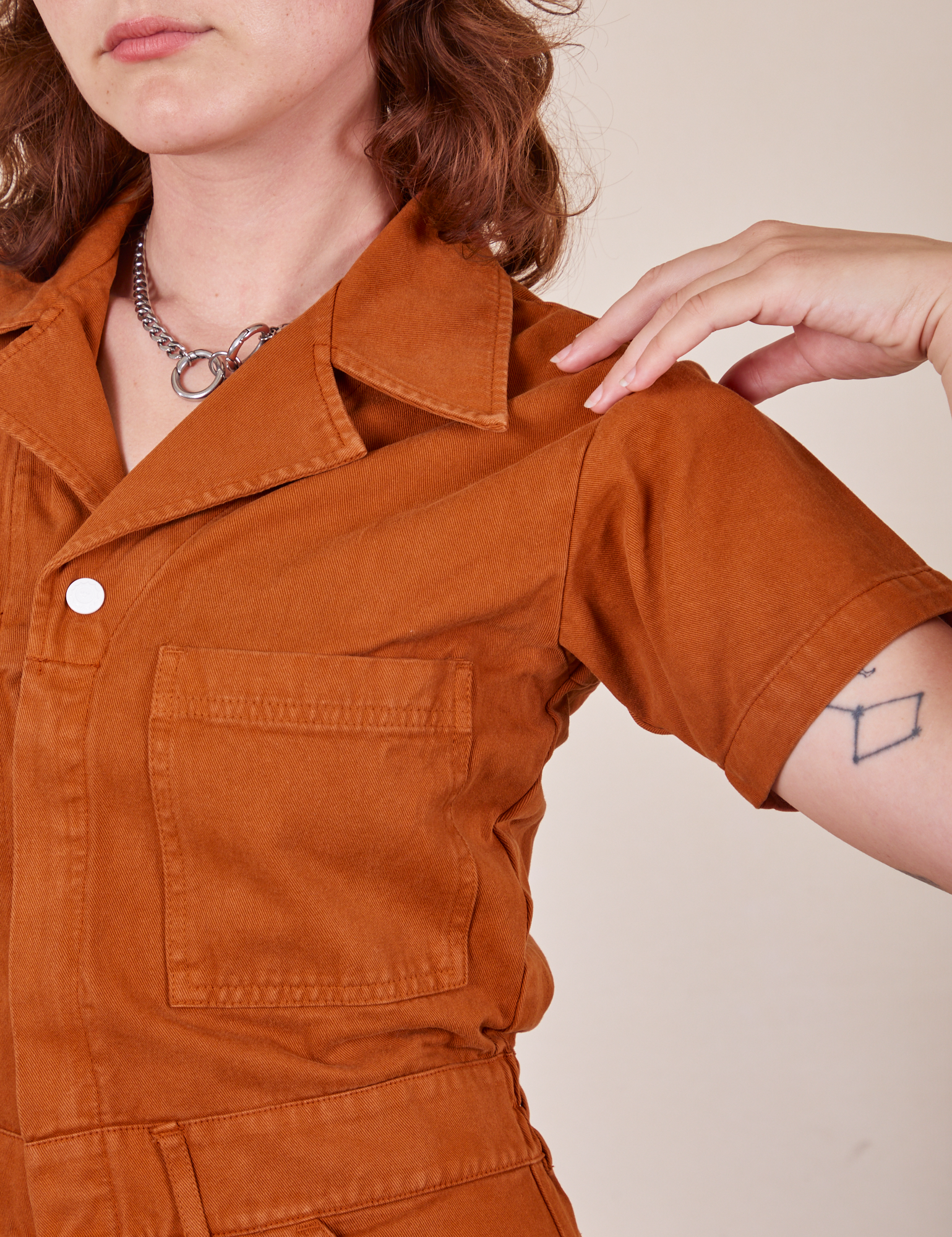 Front close up of Short Sleeve Jumpsuit in Burnt Terracotta worn by Alex