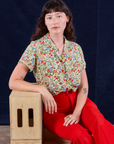 Alex is wearing Off-White Strawberry Pantry Button-Up paired with mustang red Western Pants
