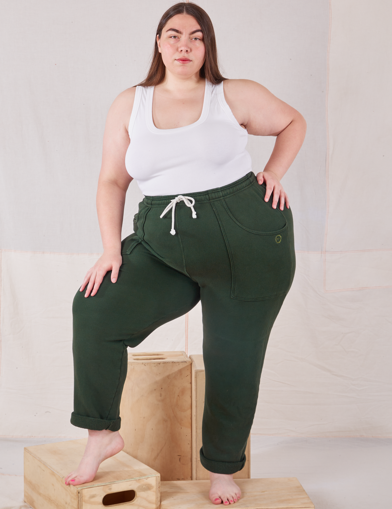 Marielena is 5&#39;8&quot; and wearing 1XL Rolled Cuff Sweat Pants in Swamp Green paired with Cropped Tank in vintage tee off-white