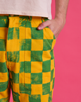Close up of Quinn's hand in the pocket of Checkerboard Work Pants in Green/Yellow