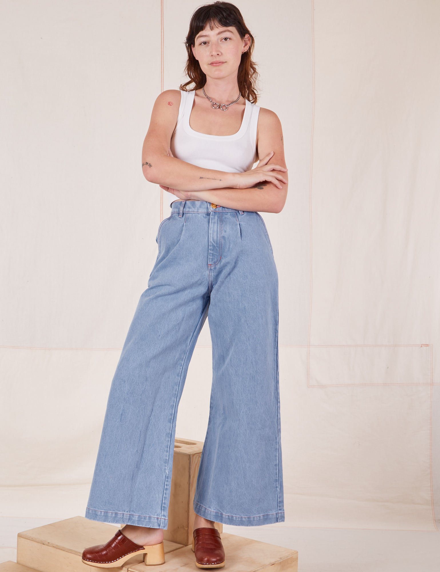 Alex is wearing Indigo Wide Leg Trousers in Light Wash and vintage off-white Cropped Tank Top