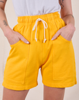 Sweat Shorts in Sunshine Yellow front close up with Alex's hands in both pockets.
