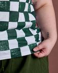 Checker Organic Tee in Swamp Green bottom close up with Ashley holding the hem