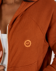 Cropped Zip Hoodie in Burnt Terracotta fabric close up of tonal embroidered sun baby logo