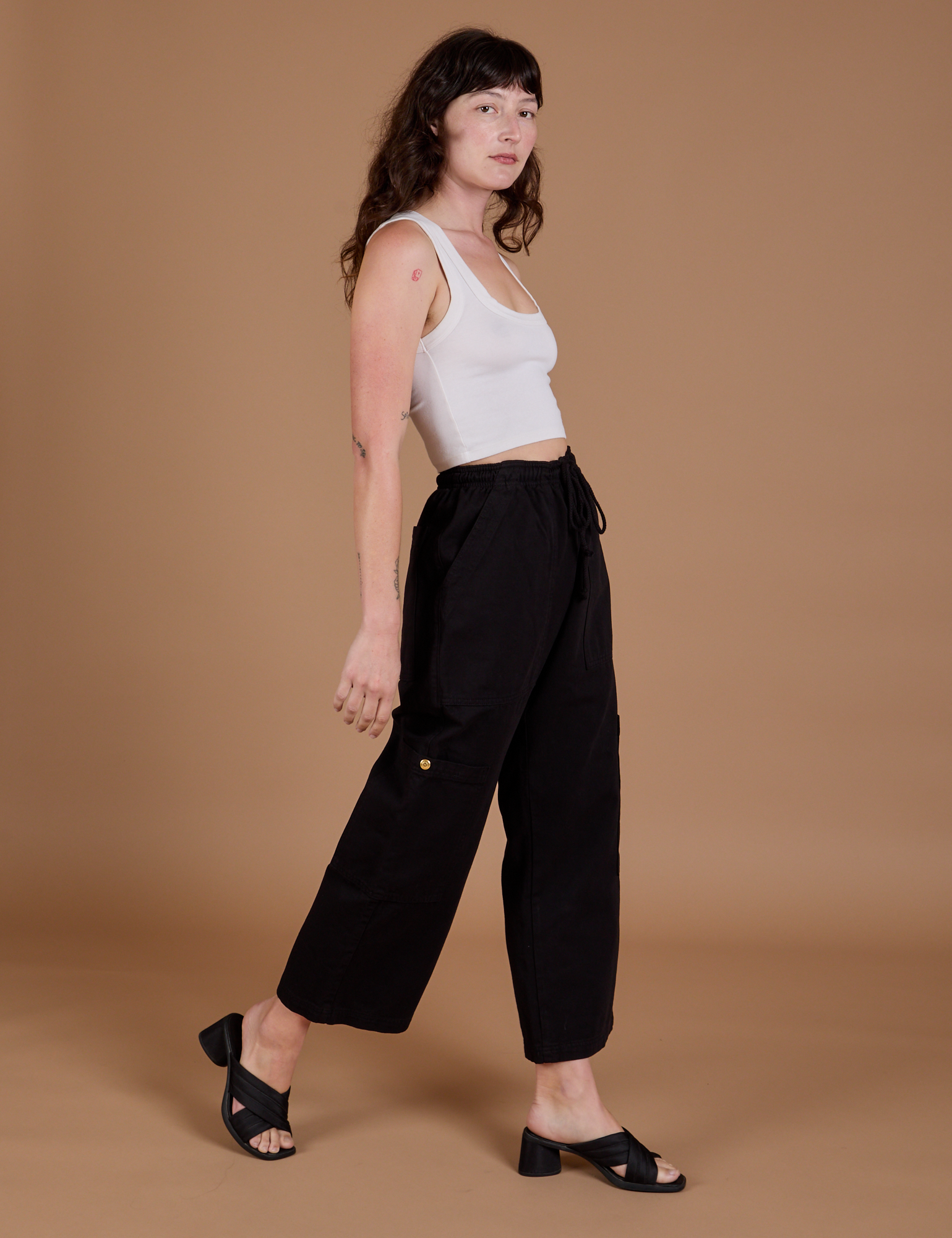 Angled front view of Drop Pocket Cargo Pants in Basic Black and Cropped Tank in vintage tee white on Alex