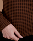 Gingham Long Sleeve Baby Tee in Fudgesicle Brown bottom close up with Alex holding the hem