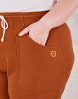 Rolled Cuff Sweat Pants in Burnt Terracotta front pocket close up. Ashley has her hand in the pocket.