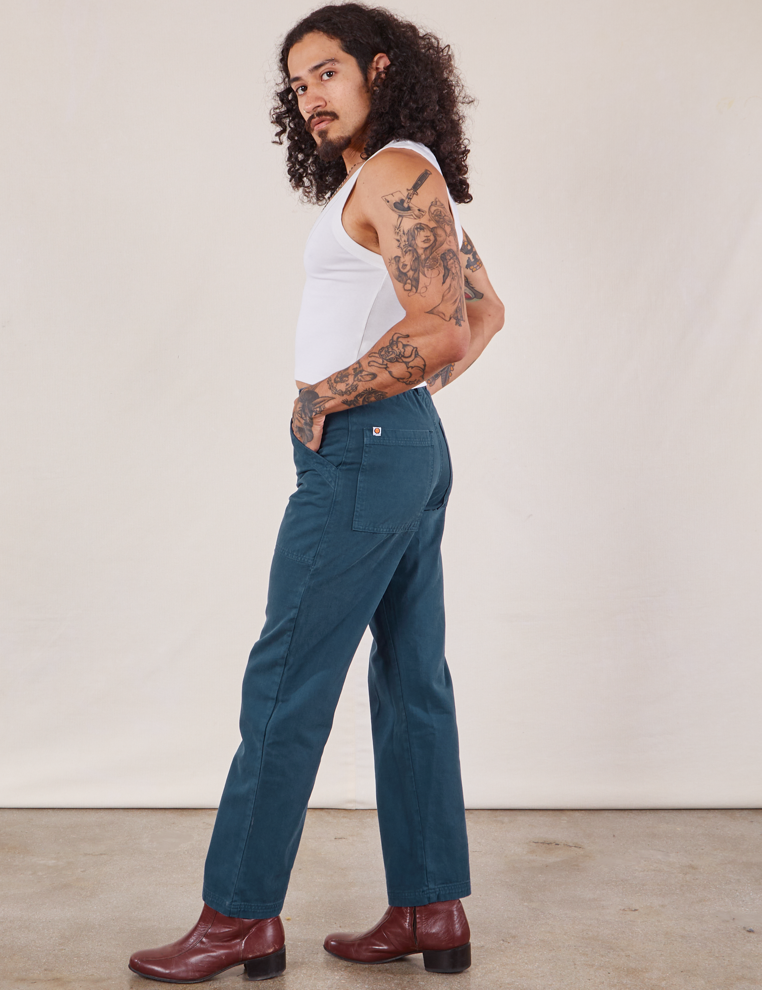 Side view of Work Pants in Lagoon and vintage tee off-white Cropped Tank on Jesse