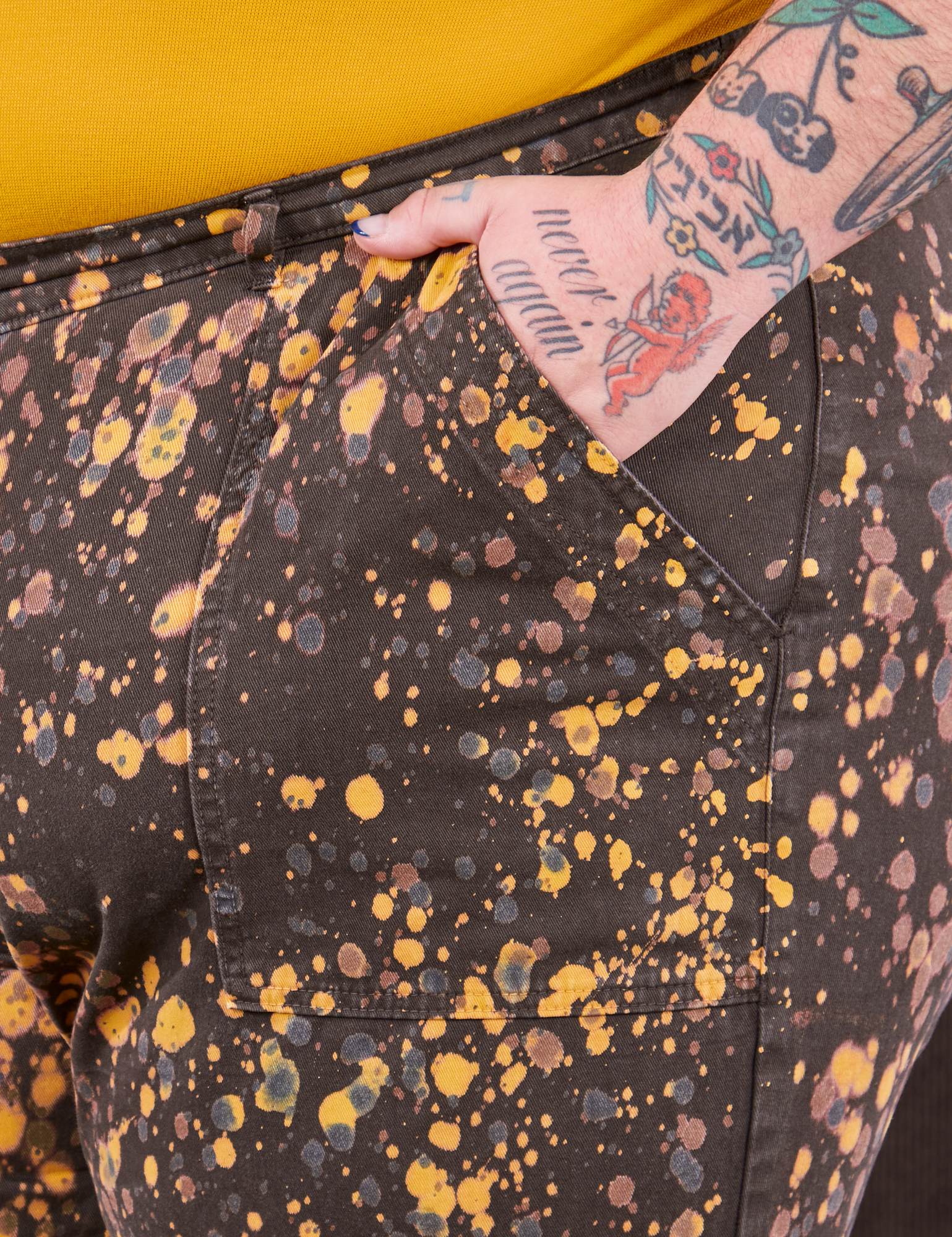 Marble Splatter Work Pants in Espresso Brown front pocket close up. Sam has their hand in the pocket.