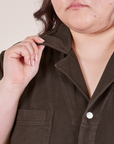 Upper front close up of Petite Short Sleeve Jumpsuit in Espresso Brown. Worn by Ashley with her hand holding onto the point of a collar