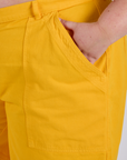 Close up of Juliet's hand in the front pocket of Longline Work Shorts in Sunshine Yellow