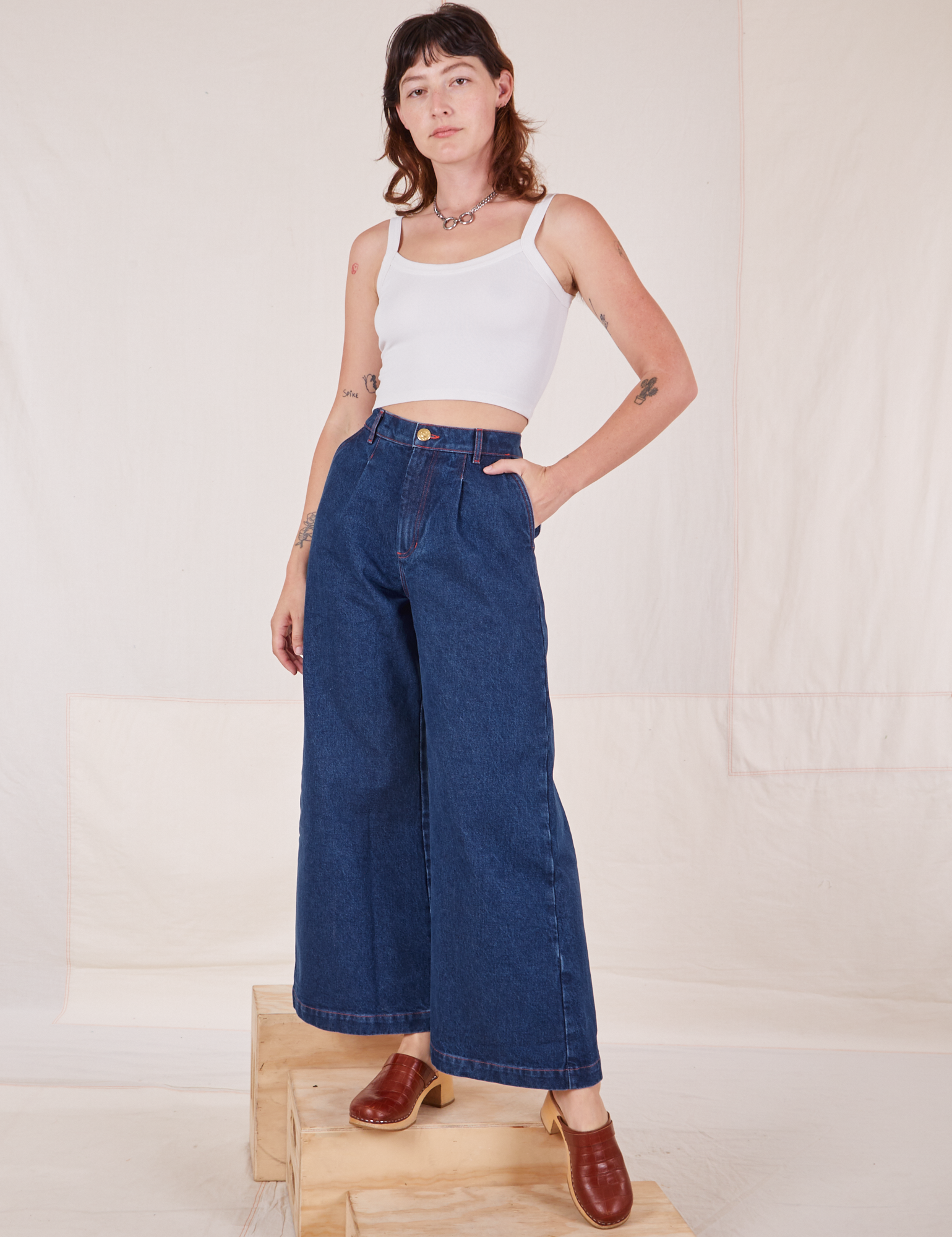 Alex is wearing Indigo Wide Leg Trousers in Dark Wash and vintage off-white Cami