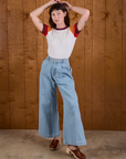 Alex is wearing Calypso Tee in Desert and light wash Indigo Wide Leg Trousers