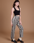 Side view of Black Stripe Work Pants in White and black Cropped Tank on Alex