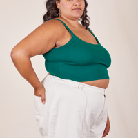 Angled view of Cropped Cami in Hunter Green and vintage off-white Western Pants worn by Alicia