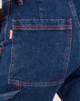 Carpenter Jeans in Dark Wash back pocket close up. Red contrast stitching on pocket and near seams.