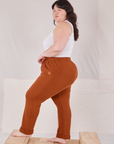 Side view of Rolled Cuff Sweat Pants in Burnt Terracotta and vintage off-white Cropped Tank Top on Ashley