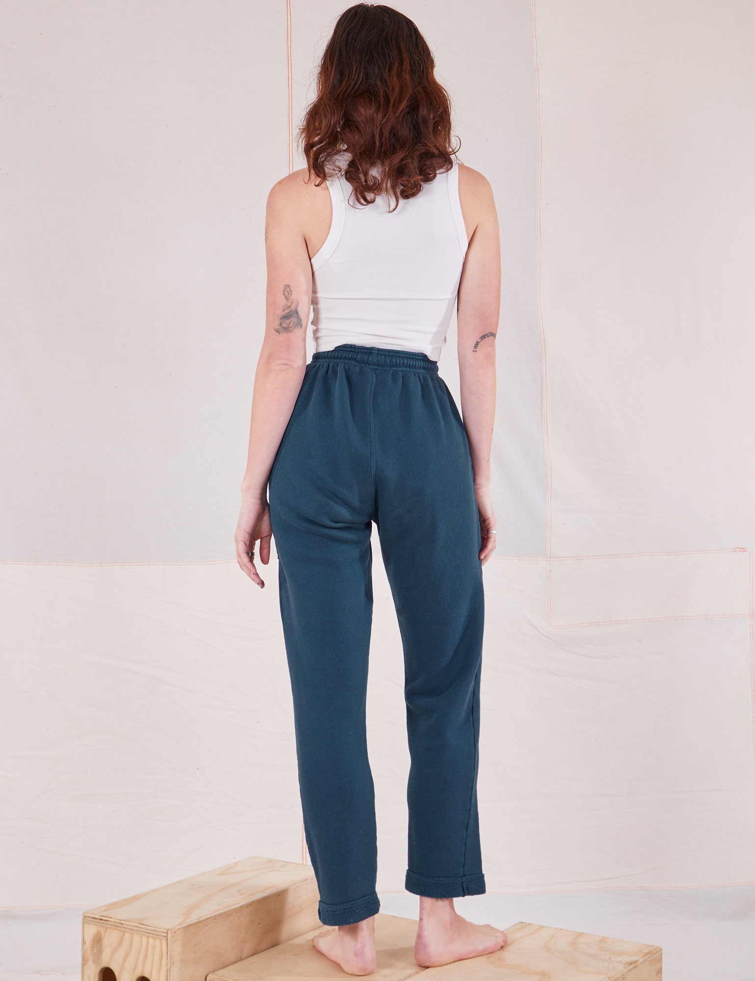 Back view of Rolled Cuff Sweat Pants in Lagoon and Cropped Tank in vintage tee off-white on Alex