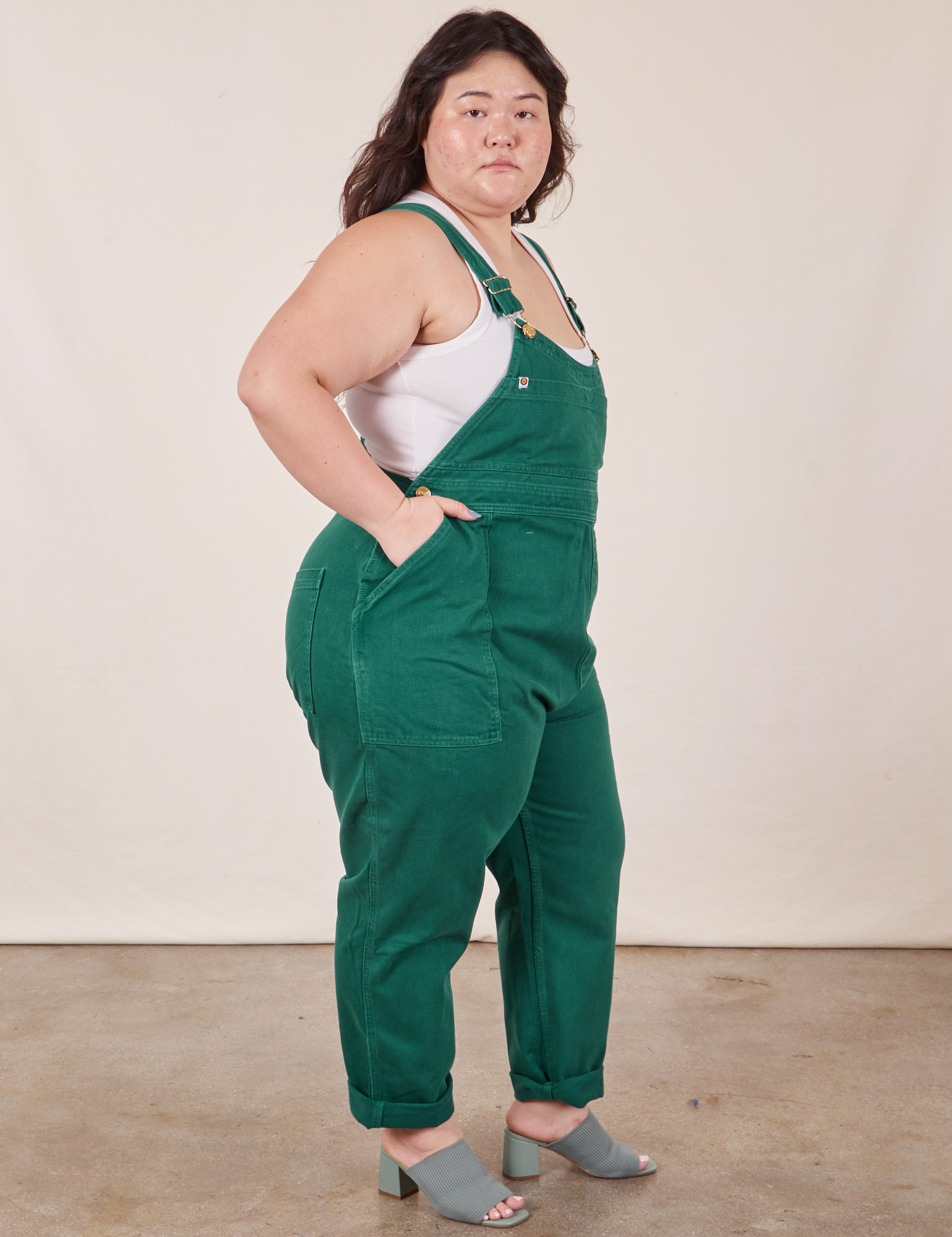 Side view of Original Overalls in Mono Hunter Green and vintage off-white Cropped Tank Top worn by Ashley