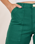 Front pocket close up of Work Pants in Hunter Green. Tiara has her hand in the pocket.